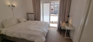 a bedroom with a white bed and a window at Knokke zeedijk met frontaal zeezicht nabij Rubensplein en casino, 20m van strand in Knokke-Heist