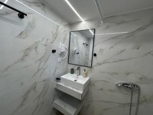 a white bathroom with a sink and a mirror at Afroditi Haus Sarti in Sarti