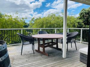 a wooden deck with a table and chairs on a porch at A peaceful oasis in Dunedin