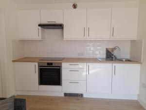 a kitchen with white cabinets and a sink at Sunray in Langton Matravers