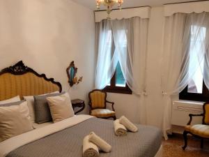 a bedroom with a bed and two chairs and windows at Ca Donzela in Venice