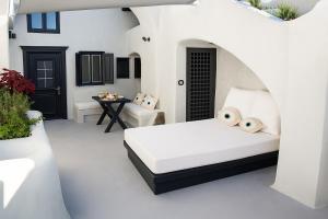 a white bedroom with a bed and a table at Selora Cave in Pyrgos