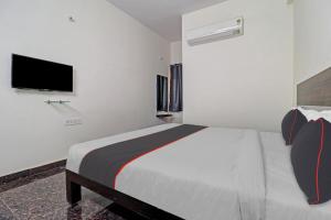 Un dormitorio blanco con una cama y un televisor de pantalla plana. en Super Collection O SS Metro Ritz, en Hyderabad