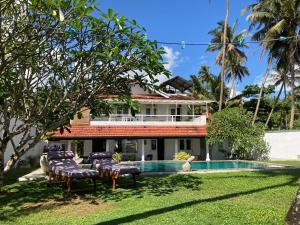 a villa with a swimming pool and lawn at Reef House in Kamburugamuwa