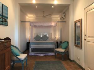 a bedroom with a bed and two chairs at Reef House in Kamburugamuwa
