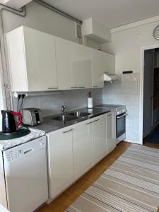 a kitchen with white cabinets and a sink at Rantaraitti in Savonlinna