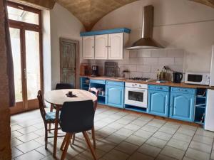 a kitchen with blue cabinets and a table with chairs at Studio Proche Pont du Gard in Remoulins