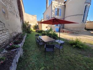 a table and chairs with an umbrella in a yard at Appartement de charme dans une maison de maître in Surgères