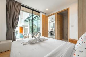 2 cygnes blancs assis sur un lit dans une chambre dans l'établissement V190 Tropical Oasis 3BR Villa with Pool & Bathtub, à Ban Saiyuan (1) 17 autres photos