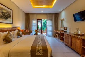 een slaapkamer met een groot bed en een bureau bij Radha Phala Resort & Spa in Ubud +24 foto's
