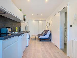 a kitchen with white cabinets and a blue chair at Suite Zen Attitude - Appartement central in Argenteuil