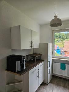 cocina con armarios blancos y microondas negro en Ferienwohnung Sülzhayn, en Sülzhayn