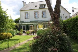 a white house with a tree in the yard at Au Fil de l'Aulne in Châteauneuf-du-Faou