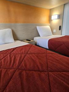 a hotel room with two beds with red sheets at Premiere Classe Strasbourg Ouest in Strasbourg +18 photos