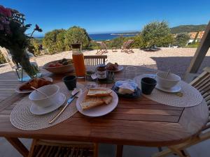 a wooden table with a breakfast of bread and toast at Appartement vue mer Vulpaghja 01 in Cargèse