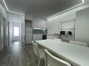 a white kitchen with a white table and chairs at Villa Rosa in Jerez del Marquesado