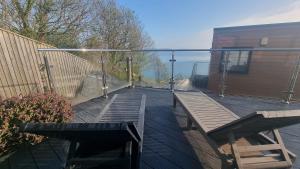 a deck with two wooden benches and a fence at TWIN COVES at Curlew 1, The Cove, Brixham in Brixham