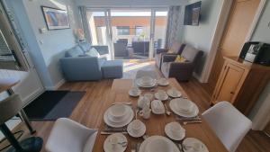 a living room with a table with white dishes on it at TWIN COVES at Curlew 1, The Cove, Brixham in Brixham +7 photos