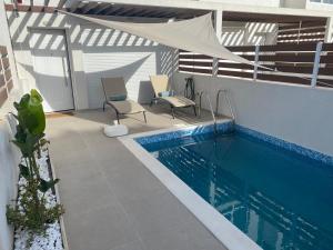 a swimming pool with two chairs and a tent at Summer Stories Kallithea in Kallithea Halkidikis