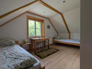 a bedroom with a bed and a desk and a window at W Starym Sadzie in Białowieża
