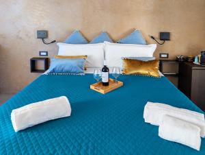 a large blue bed with a bottle of wine on it at La Piazzetta Luxury Rooms in Polignano a Mare
