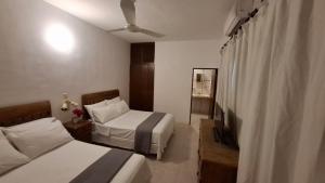 a hotel room with two beds and a ceiling fan at Casa del Viento Celestun in Celestún