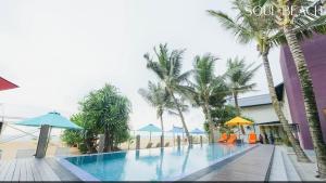 a swimming pool with palm trees and blue umbrellas at Soul Beach Colombo in Dehiwala