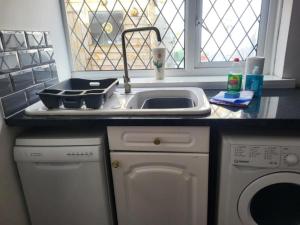 a kitchen with a sink and a washing machine at 2 bed flat sleeps 4 Swansea centre in Swansea +5 photos
