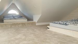 a attic bedroom with two beds and a window at Domek pod sosnowym lasem in Borowy Młyn