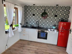 a kitchen with a red refrigerator and white cabinets at Domek pod sosnowym lasem in Borowy Młyn +8 photos