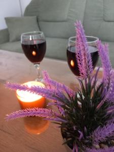 a table with two glasses of wine and purple flowers at Apartman LAVANDA in Teslić