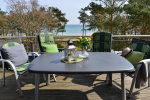 a table and chairs on a deck with a view of the ocean at Ferienwohnung Admiralssuite in Juliusruh