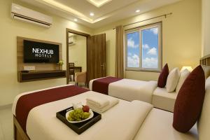 a hotel room with two beds with a tray of fruit at Nexhub Luxe57 1BHK- Golf Course Road in Gurgaon