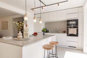 une cuisine avec des placards blancs et deux tabourets dans l'établissement Luxus-Ferienhaus DS11, à Fehmarn