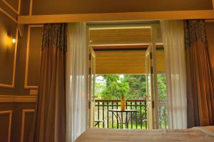 a bedroom with a bed and a view of a balcony at The Tredis Heritage by the Lake in Kodaikānāl