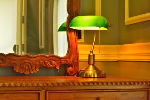 a green lamp sitting on a dresser next to a mirror at The Tredis Heritage by the Lake in Kodaikānāl