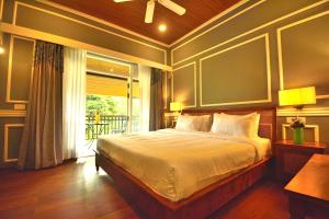 a bedroom with a large bed and a balcony at The Tredis Heritage by the Lake in Kodaikānāl