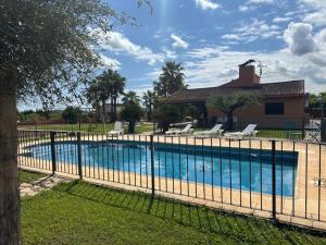 a fence around a swimming pool with chairs and a house at Casa en la naturaleza de Chella in Chella