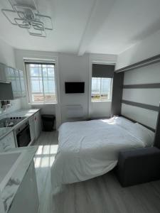 a white bedroom with a bed and a kitchen at Seafront Studio Snug by the Sea - Sea Views in South Hayling