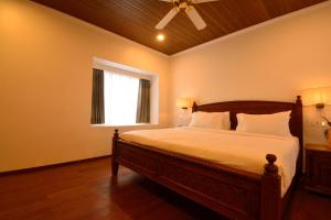 a bedroom with a bed with a ceiling fan and a window at The Tredis Heritage by the Lake in Kodaikānāl