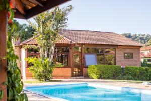 a house with a swimming pool in front of a house at Pousada Vila Minas in Itanhandu