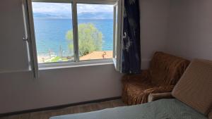 a room with a window and a chair and the ocean at Villa Shine apartment 2 in Radožda +4 photos