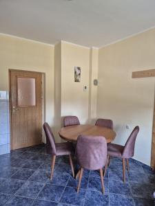 una sala da pranzo con tavolo in legno e sedie viola di Apartman KEC - Apatin a Apatin