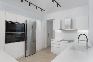 a kitchen with white cabinets and a stainless steel refrigerator at Athenian Black Villa in Saronida