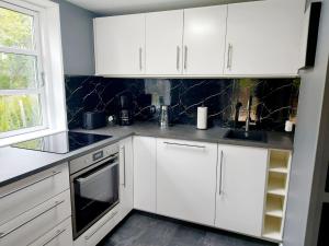 a white kitchen with white cabinets and a window at Ferienhaus Ymervägen in Lönsboda