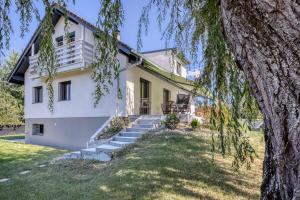 une maison blanche avec des escaliers et un arbre dans l'établissement Villa de charme proche du lac, à Sciez