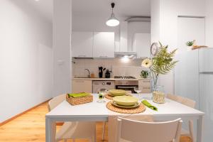 a white kitchen with a white table and chairs at A due passi dal Mare - Il Faro sul Mare in Sori +7 photos