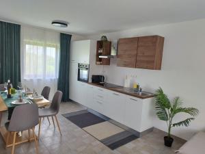 a kitchen with white cabinets and a table with a potted plant at Kuća za odmor Ria in Gornja Voća
