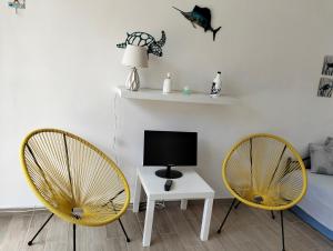 a living room with two yellow chairs and a tv at Casa Mare Ognina in Ognina