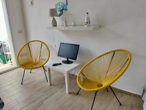 two yellow chairs and a desk with a computer monitor at Casa Mare Ognina in Ognina